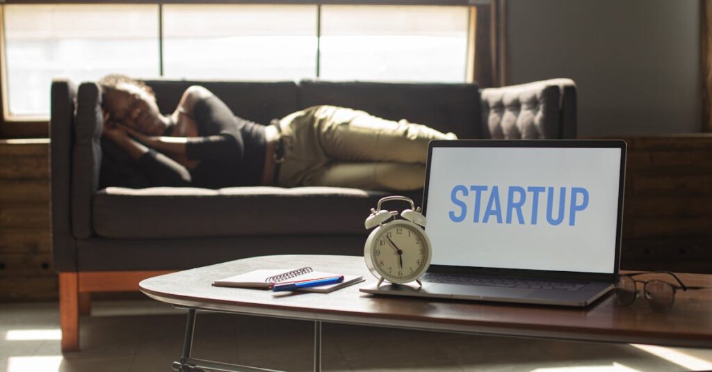 A woman lies on a sofa while a laptop displays 'STARTUP,' capturing a workspace vibe.